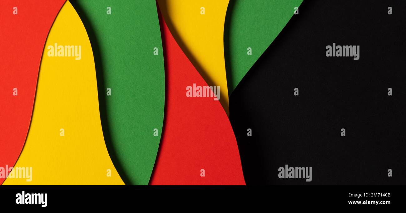 Schwarzer Hintergrund für Verlauf Monat. Abstrakte Zusammensetzung im Papierschnitt mit Lagen geometrischer Formen und wellenförmigen Linien in Rot, Gelb und Grün Stockfoto