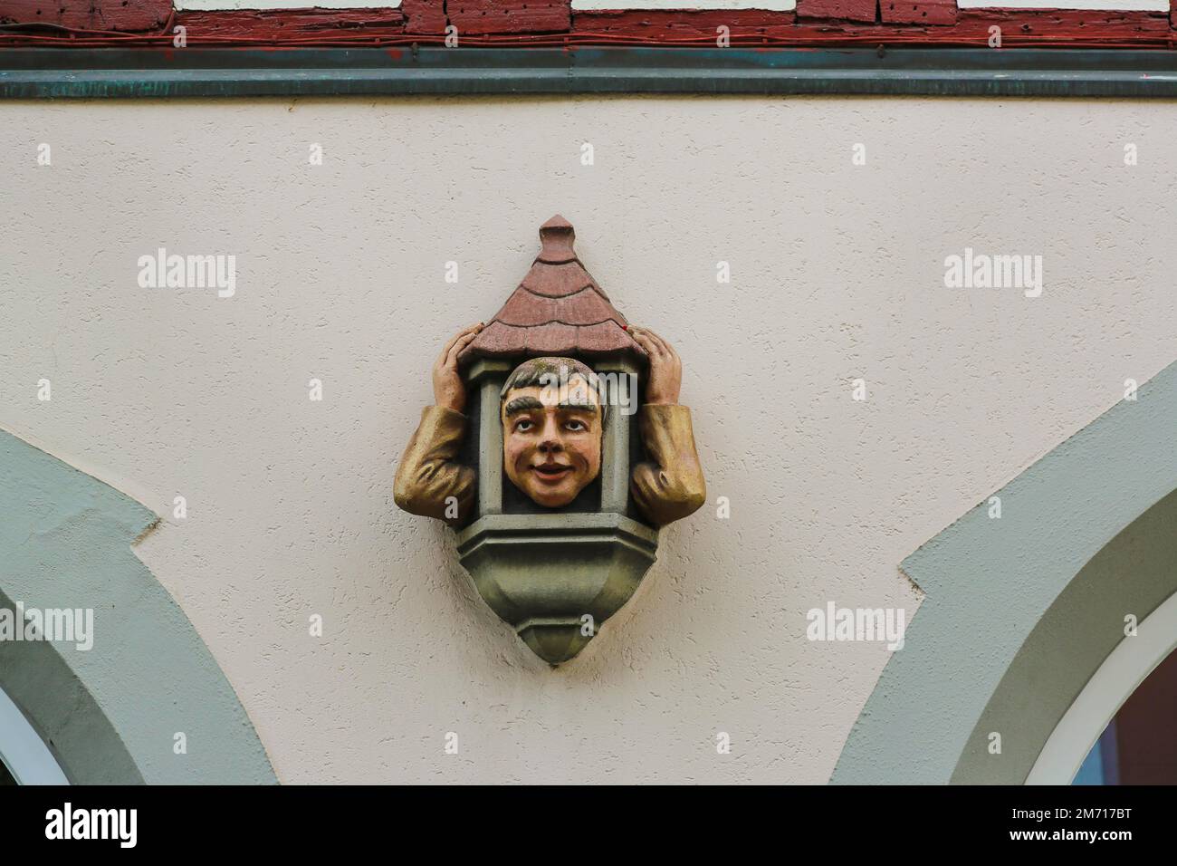 Figur, Kopf und Arme eines lustigen Mannes mit Hausdach, Dekoration am Gebäude, Fassade, Wanddekoration, Ueberlingen am Bodensee Stockfoto