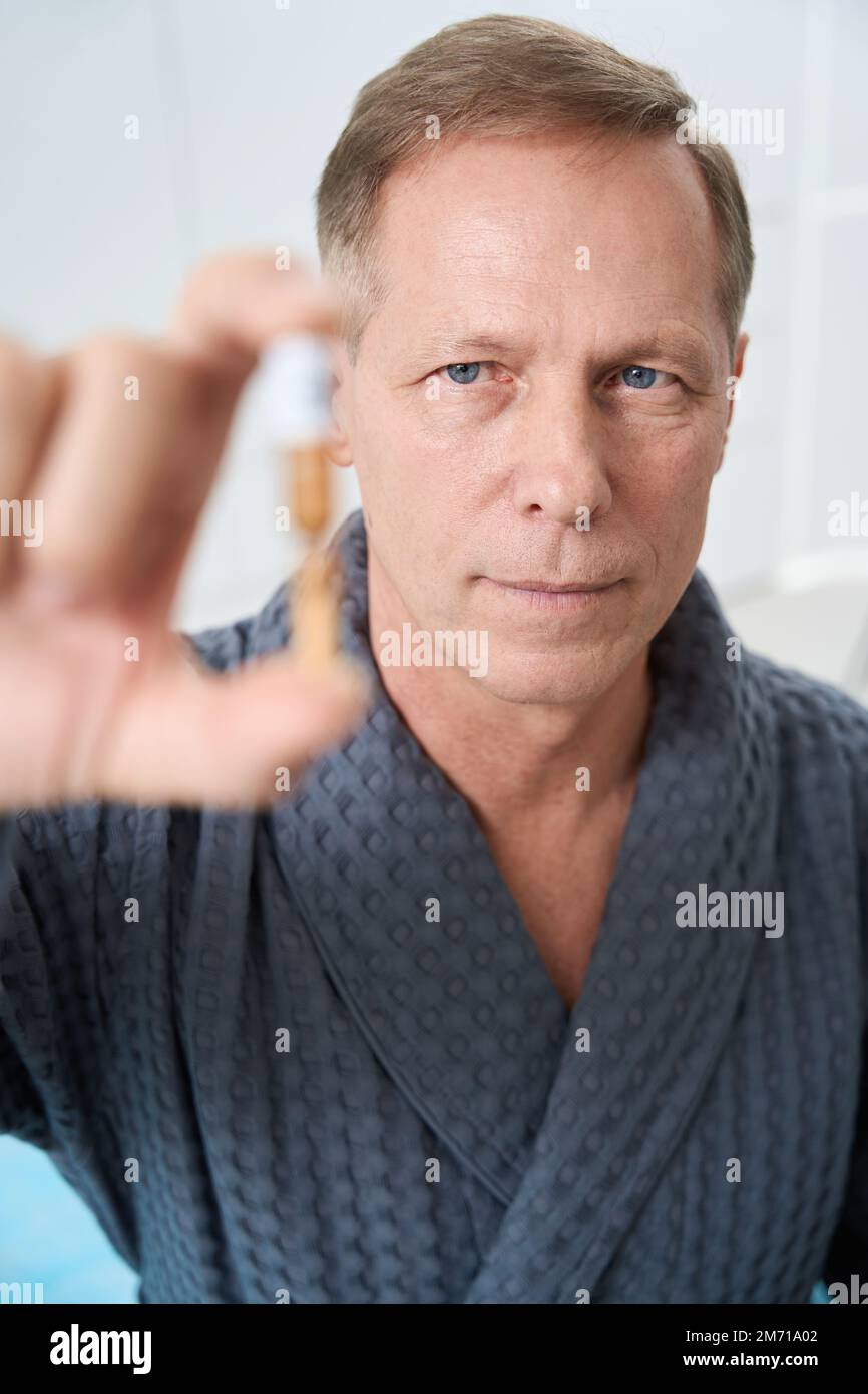 Ein seriöser Mensch hält Ampullen mit moderner Medizin in den Händen Stockfoto