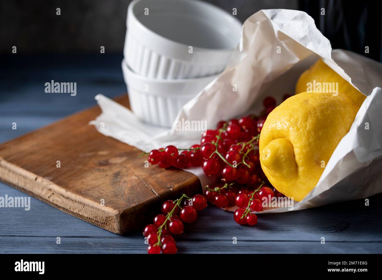 Frisch gekaufte Zitronen und rote Johannisbeeren in Papiertüte und weiße Gratiniergerichte Stockfoto