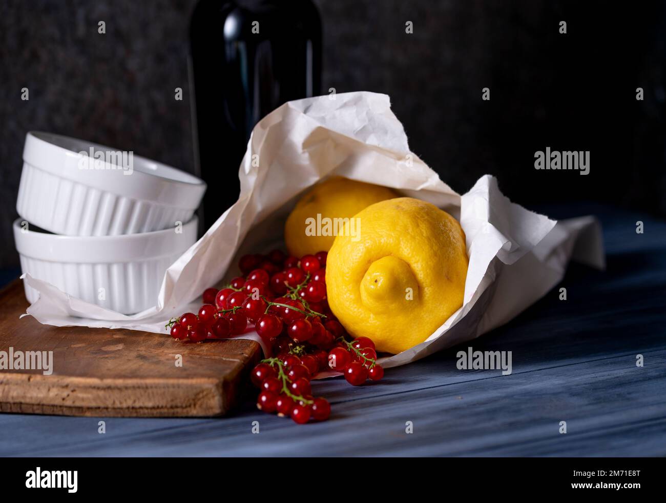 Frisch gekaufte Zitronen und rote Johannisbeeren in Papiertüte und weiße Gratiniergerichte Stockfoto