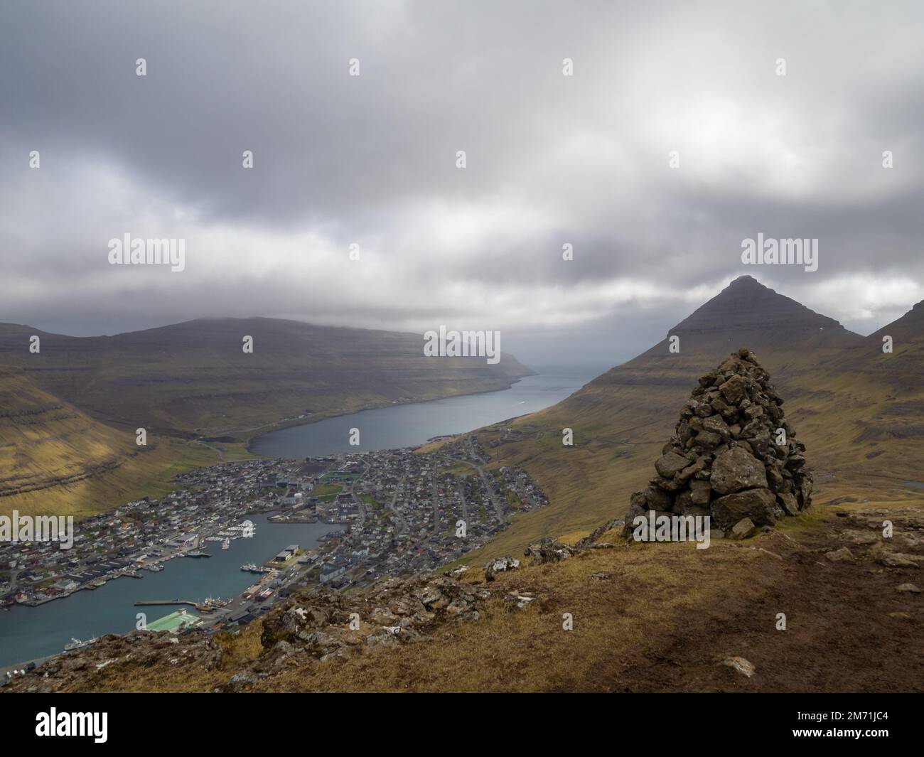 Ein Cairn auf dem Klakkur Bergwanderweg, mit Klaksvik unten am Horizont Stockfoto