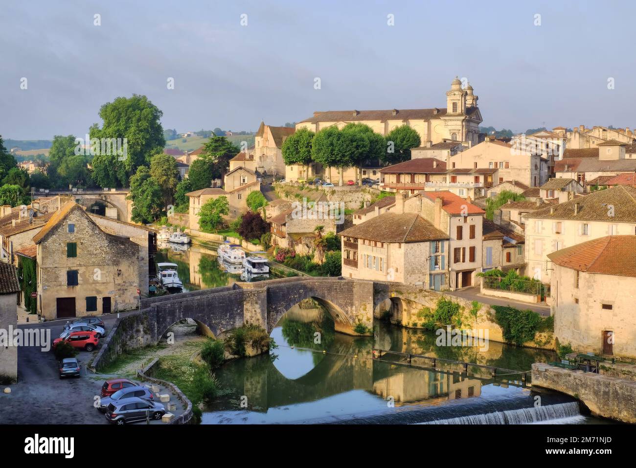 Nerac: Kirche Saint-Nicolas, Stadt, Kanalboote, Brücken und Fluss Petit Baise mit Spiegelreflexionen kurz nach Sonnenaufgang in Nerac, Frankreich Stockfoto