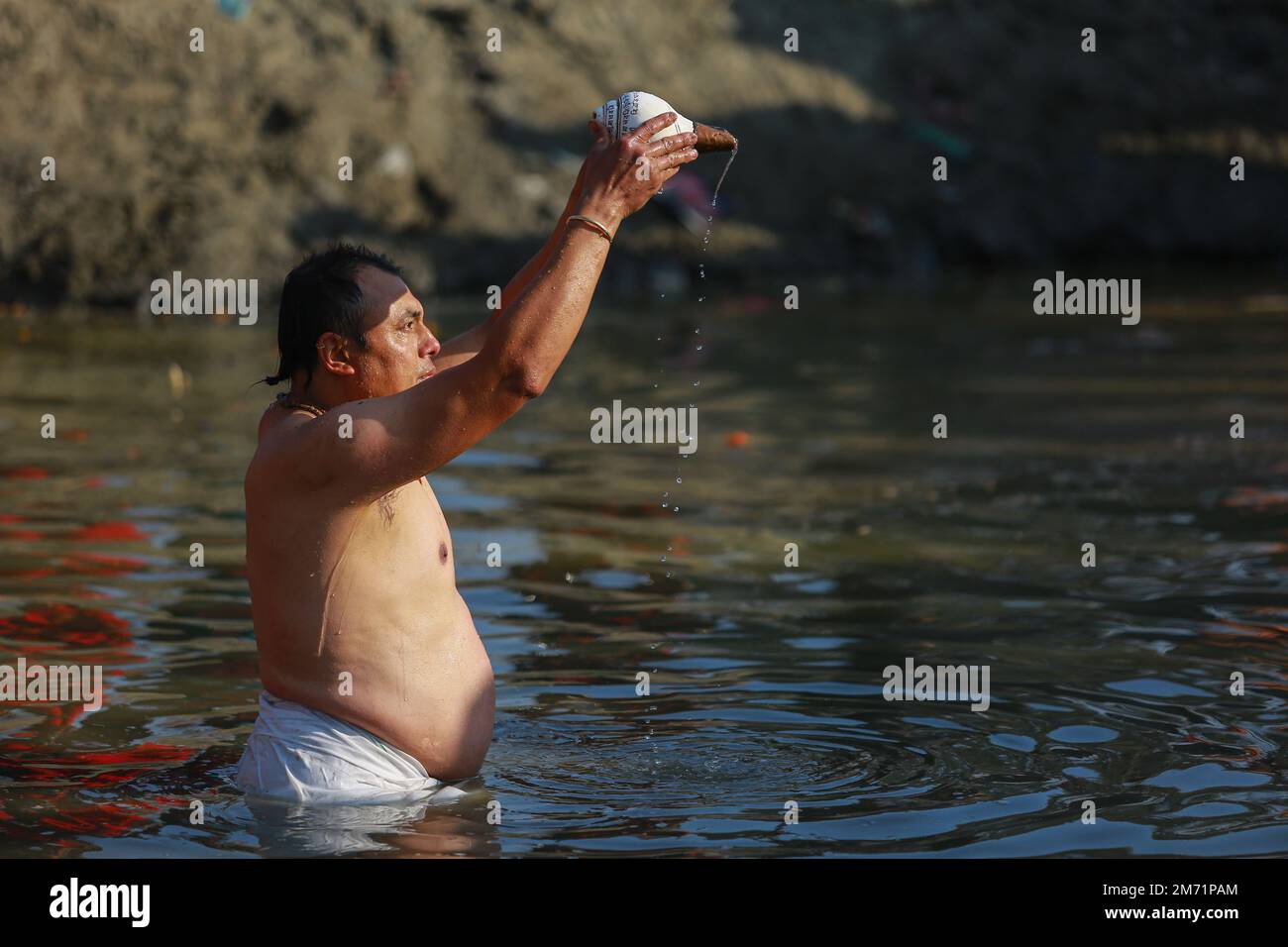 Nepal. 6. Januar 2023. Ein Gläubiger bietet Wasser an die Sonne, auch bekannt als Arga, der im Hanumante River, Bhaktapur, untergetaucht ist, anlässlich des Beginns von Shree Swasthani Brata Katha, einem monatelangen Festival, das der Göttin Swasthani und Gott Madhav Narayan am Freitag gewidmet ist. Während des einmonatigen Rituals werden die Geschichten von Göttin Swasthani, Gott Shiva und anderen Göttern erzählt, während die Gläubigen die Heilige Schrift vortragen und für das Wohlergehen ihrer Ehepartner beten. Die Rituale im Zusammenhang mit der Swasthani Katha finden am Ufer von Flüssen in verschiedenen Hindu-Schreinen auf der anderen Seite des Landes statt Stockfoto