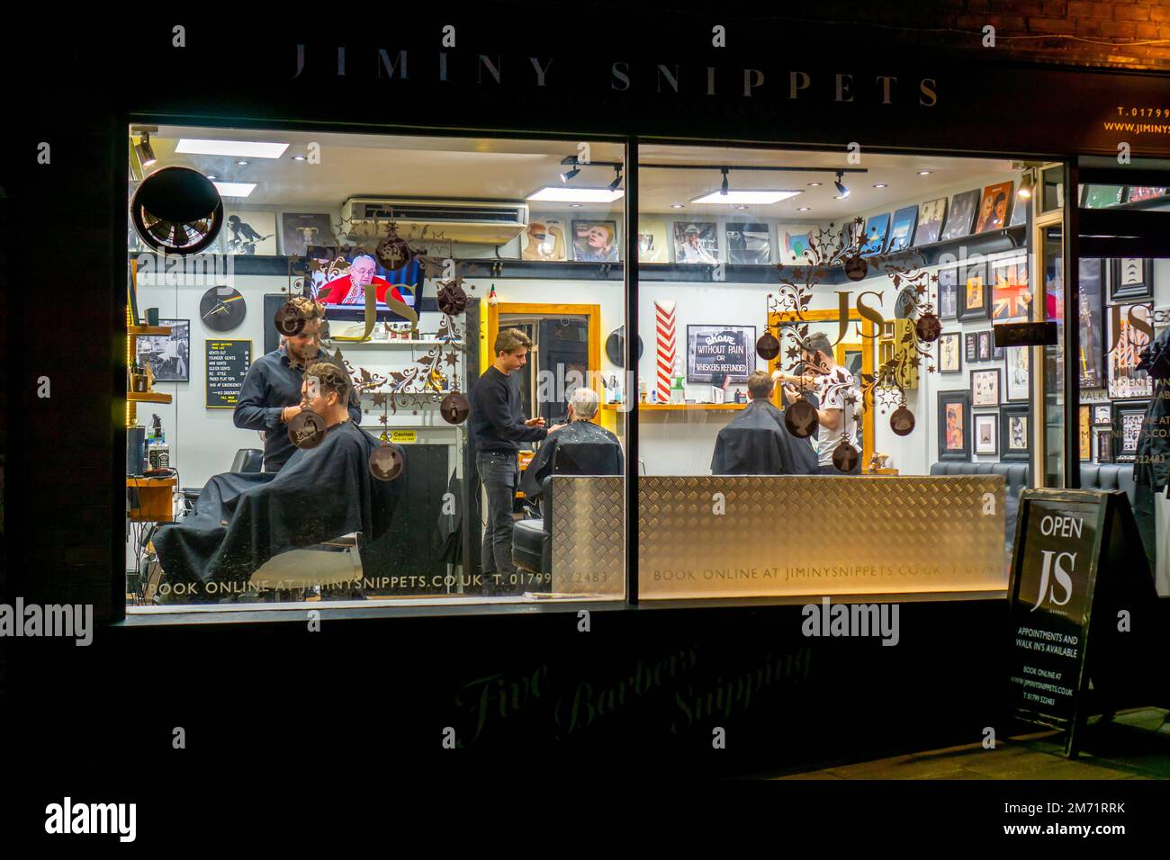 Männer lassen sich nachts in einem Friseurladen in Saffron Walden Haare schneiden Stockfoto