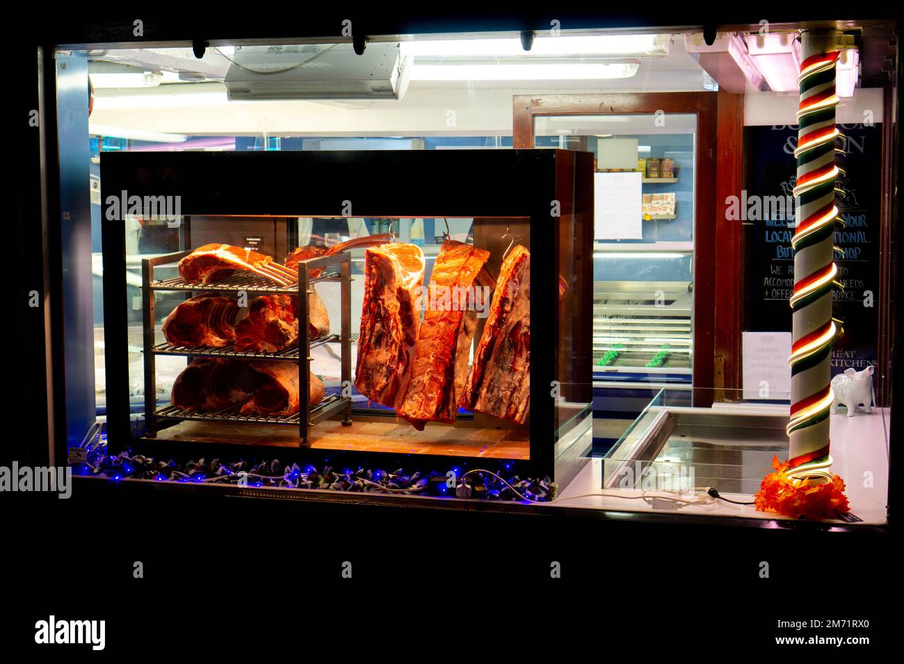Fleischstücke in einem Schaufenster, das nachts in Saffron Walden beleuchtet war Stockfoto