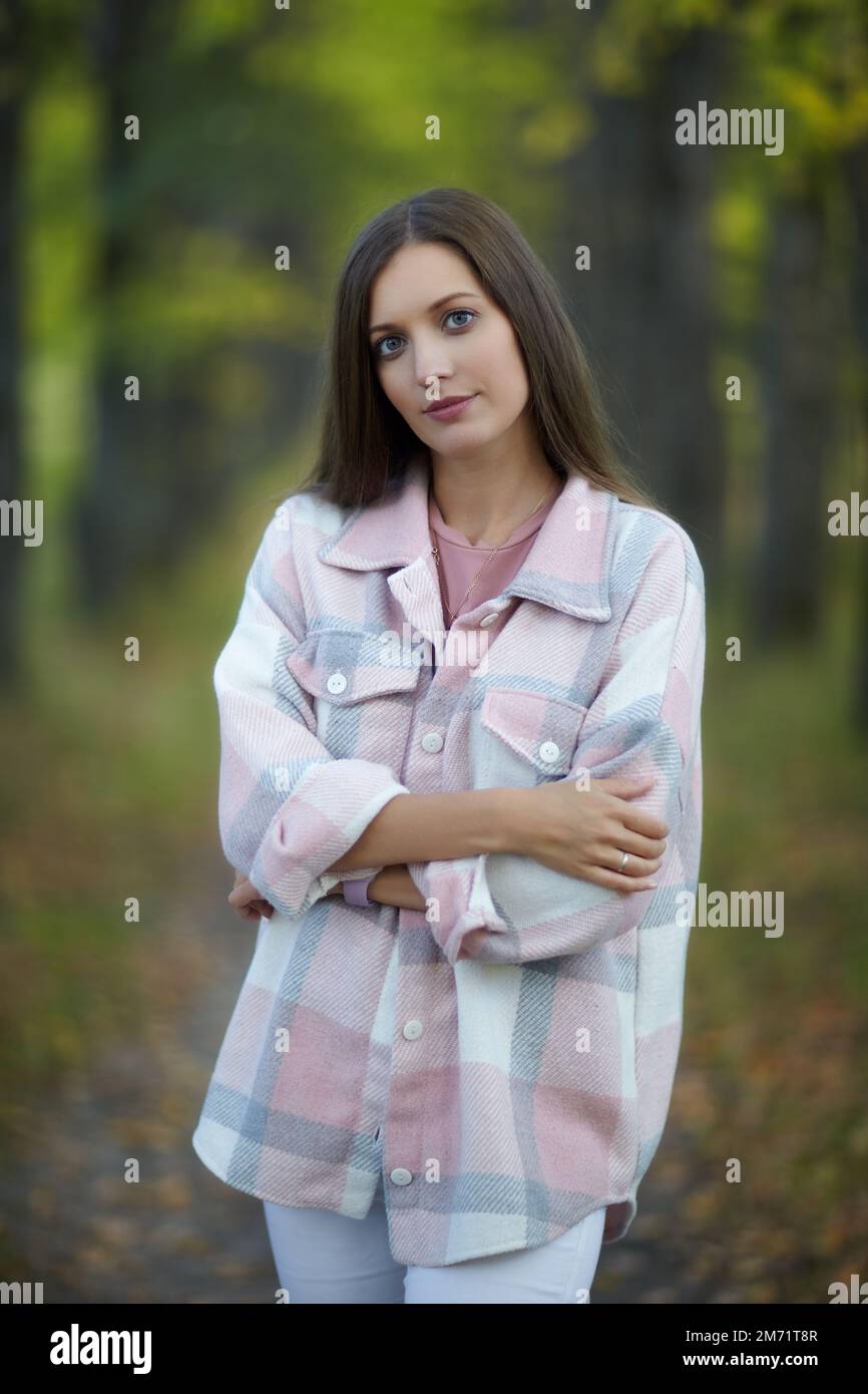 Blonde Frau in lässigen Kleidern, die im Herbst auf einer Lindenallee spaziert. Pfad unter gelben Bäumen mit herbstlichen Blättern. Sonniger Herbsttag. T Stockfoto