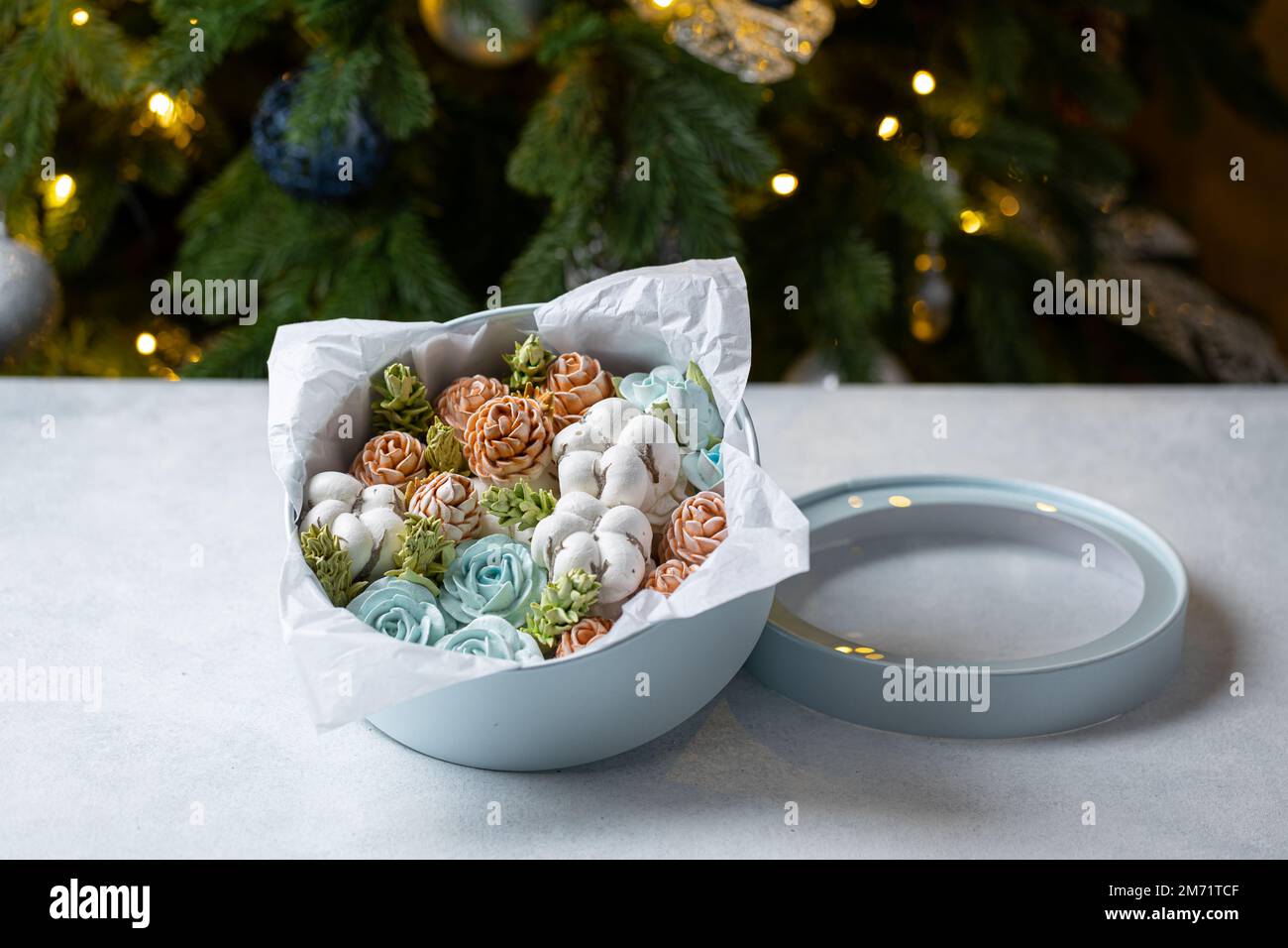 Marshmallow-Blumenstrauß in einer Geschenkbox auf dem Hintergrund eines Weihnachtsbaums, das Konzept einer festlichen Stimmung. Stockfoto
