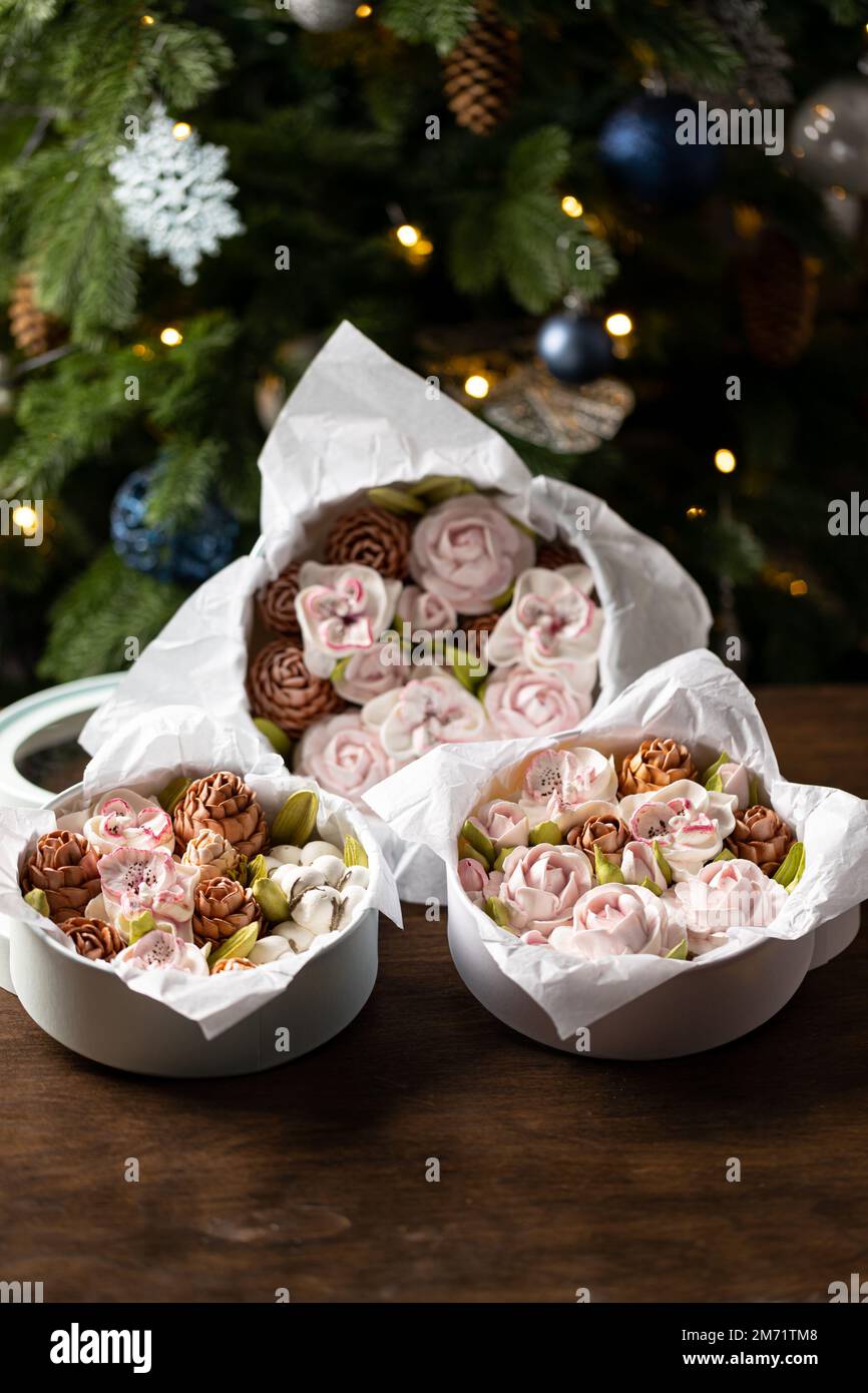 Marshmallow-Blumenstrauß in einer Geschenkbox auf dem Hintergrund eines Weihnachtsbaums, das Konzept einer festlichen Stimmung. Stockfoto