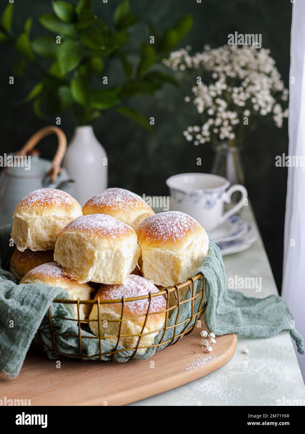 Hausgemachte Milch und Käsesahne in einem Korb mit einem Tuch neben einem Fenster Stockfoto