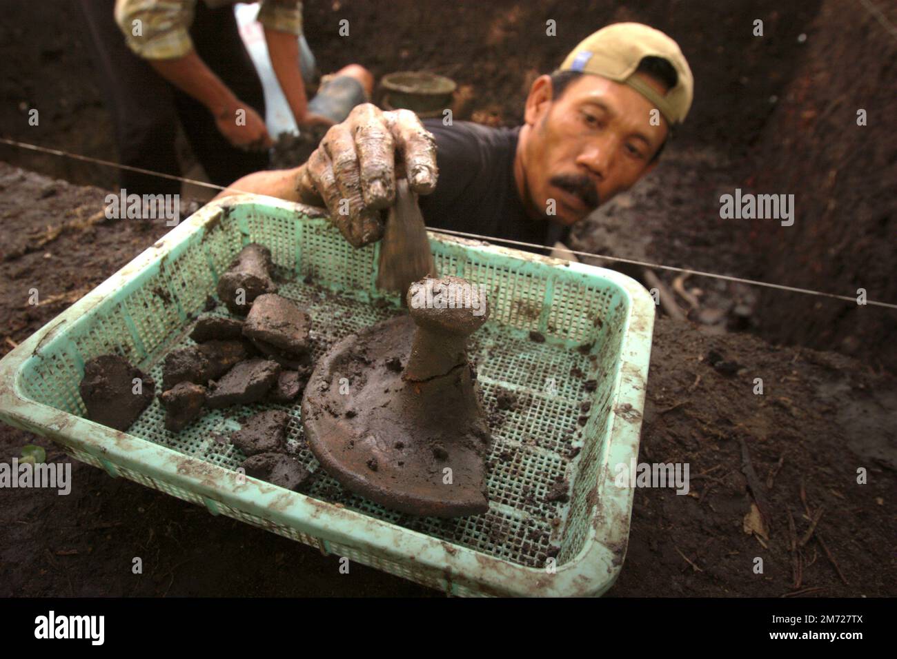 Ein Arbeiter, der während der Ausgrabung einer prähistorischen Grabstätte, die von der indonesischen National Archäology Research in Tempuran, Karawang, West Java, Indonesien durchgeführt wurde, Keramikfragmente sammelt. Stockfoto