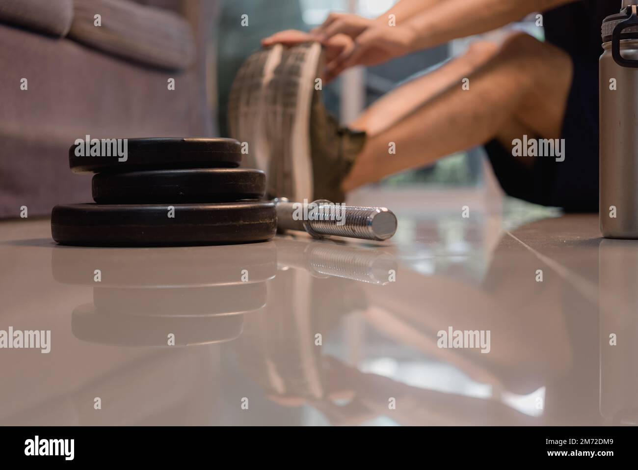 Ein Mann, der sich vor dem Fitnesstraining und dem Krafttraining im Wohnzimmer die Muskeln dehnt. Stockfoto