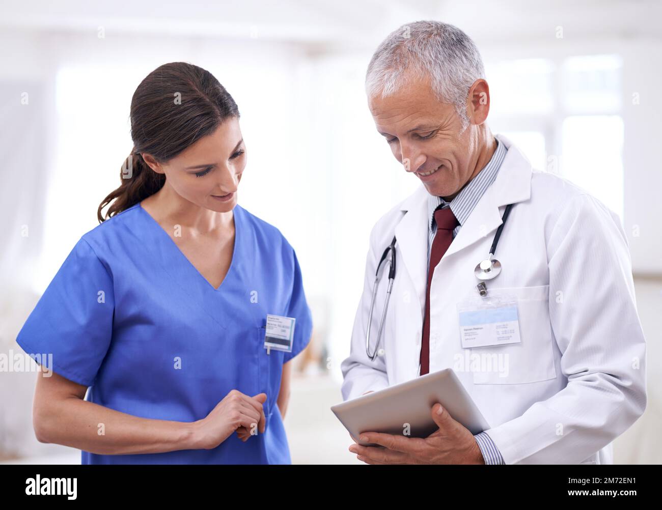 Was hältst du davon? Zwei medizinische Fachleute suchen ein digitales Tablet. Stockfoto