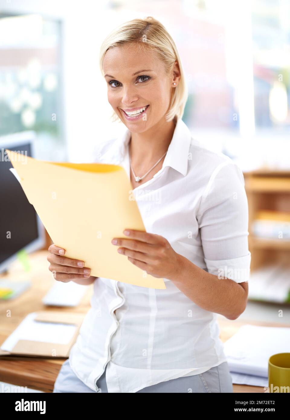 Abschließende Prüfung eines weiteren erfolgreichen Verkaufs. Porträt eines attraktiven jungen Büroangestellten, der Papierkram liest. Stockfoto