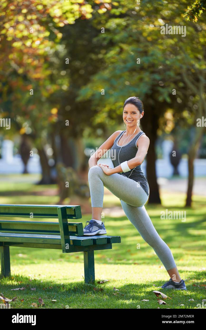 Sommerdehnung. Aufnahme einer Frau in voller Länge, die sich vor ihrem Lauf im Park streckt. Stockfoto