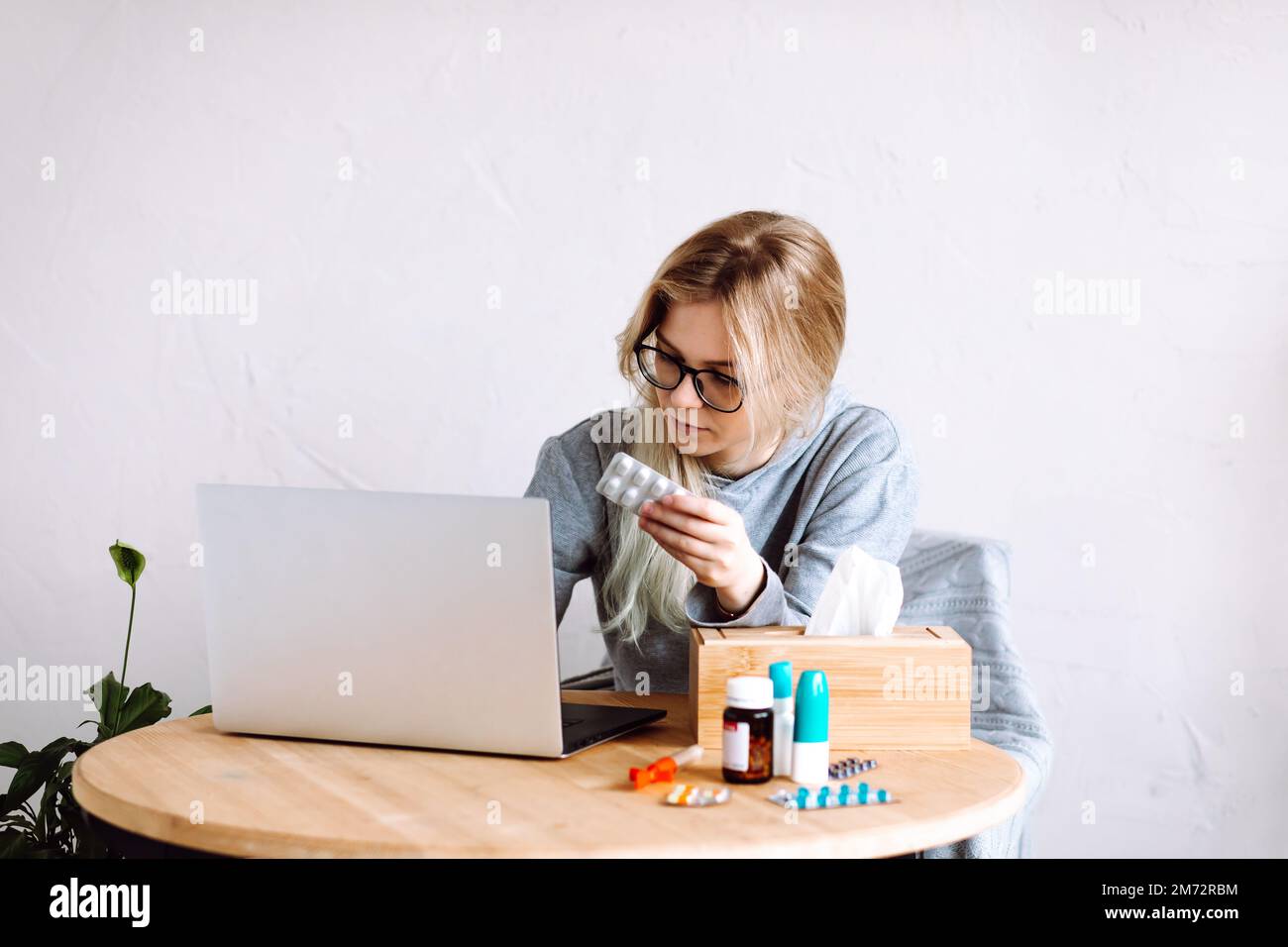 Porträt einer jungen Frau, die Pillen-Blister auf den Bildschirm zeigt, dem Arzt online zuhört, verschreibungspflichtig ist. Telemedizin. Stockfoto