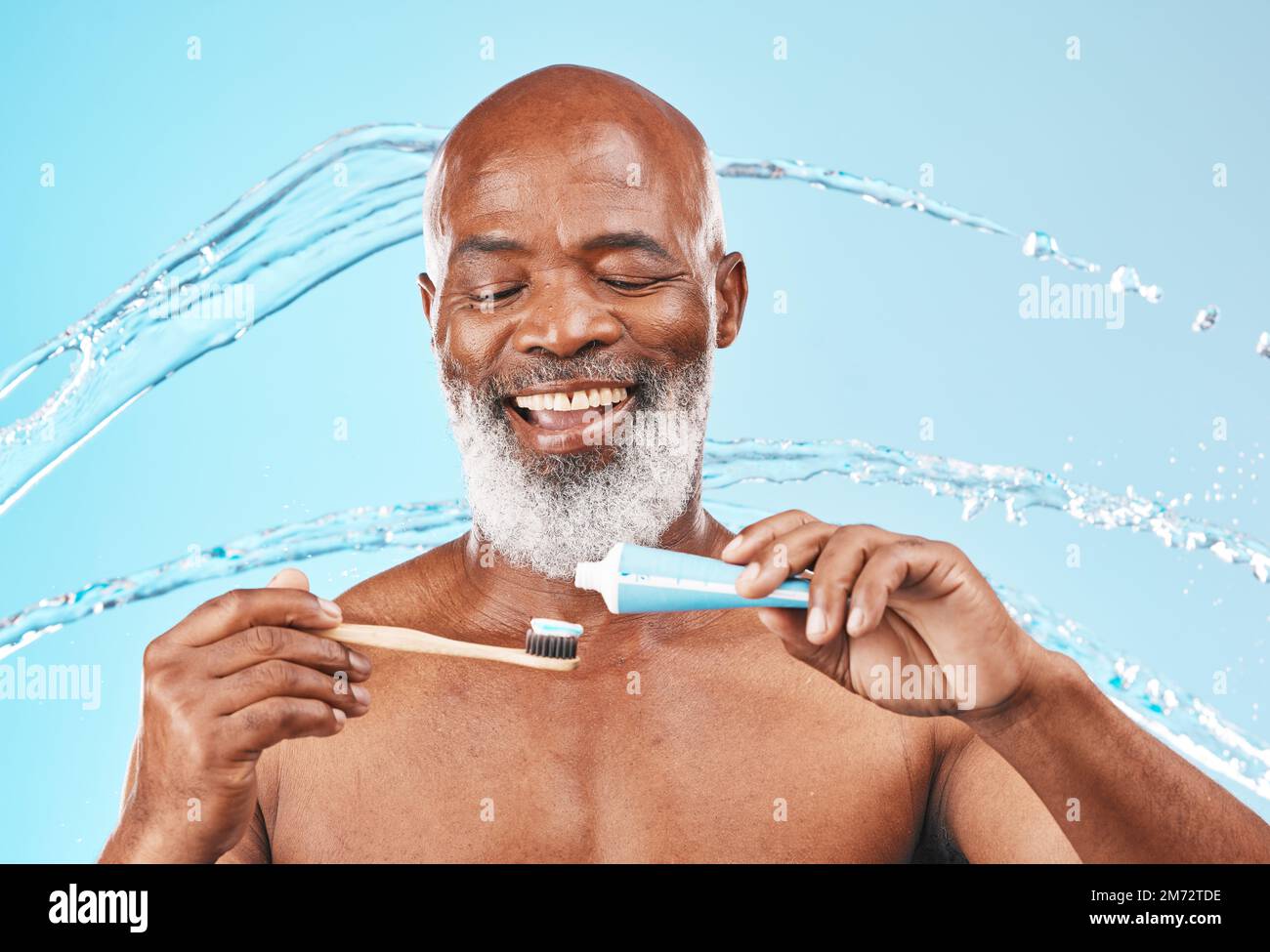 Gesicht, Wasserspritzer und schwarzer Mann mit Zahnbürste und Zahnpasta im Studio isoliert auf blauem Hintergrund. Zahn-, Mundhygiene und männliches Seniorenmodell mit Stockfoto