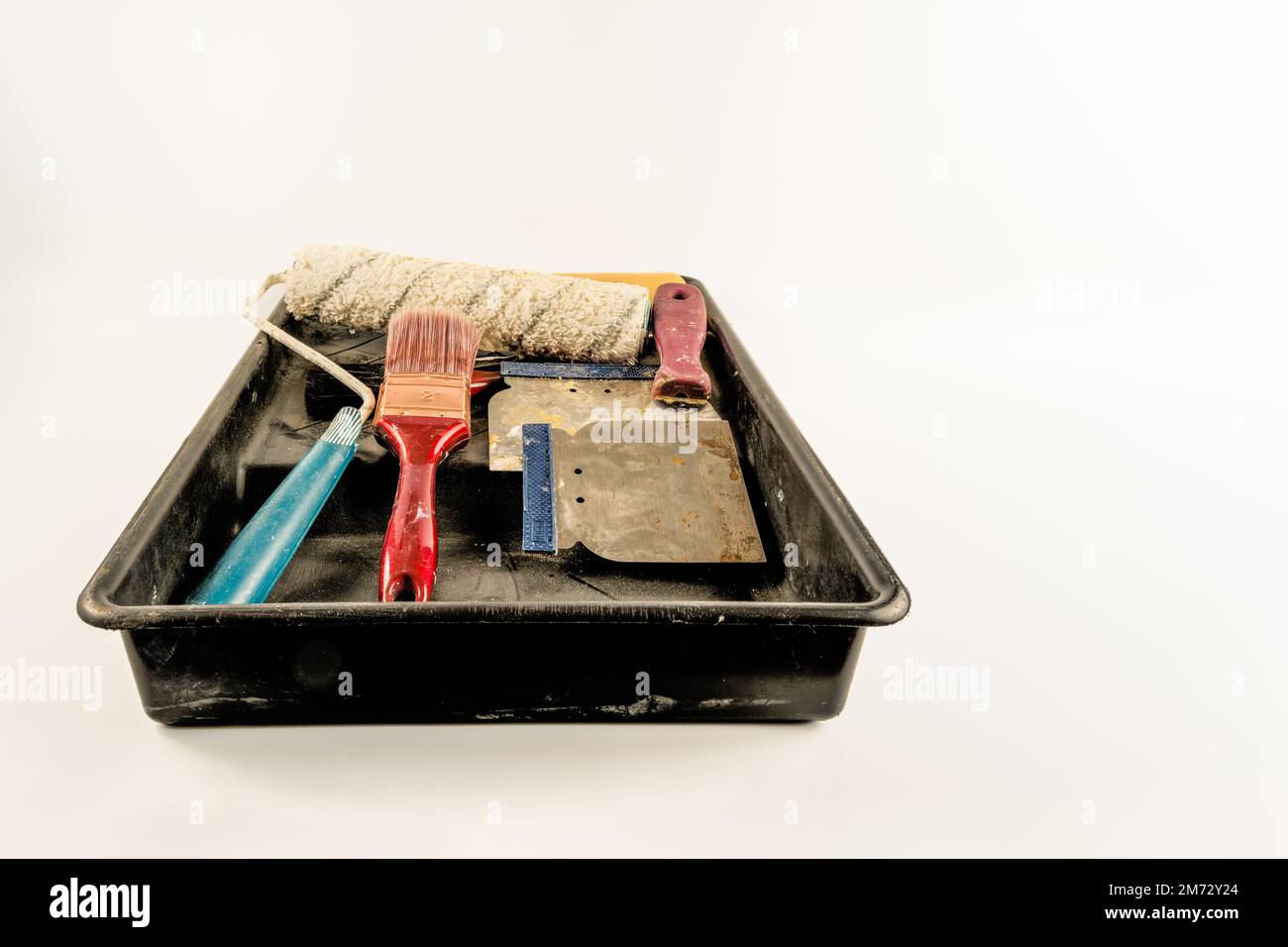 Maler- und Dekorationswerkzeuge in schwarzen Rollladenbürsten, Füllklingen, Schaber Lämmer Wollwalze isoliert auf weißem Hintergrund Stockfoto
