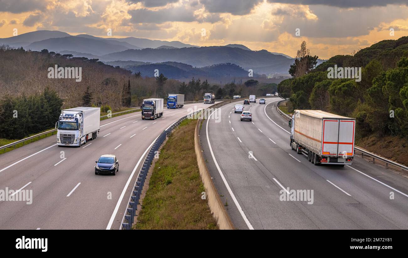 Sehen Sie über AP7 Autoroute de Mediterrania Freeway Traffic mit Güterwaggons und Weihnachtsverkehr. Katalonien, Spanien Stockfoto