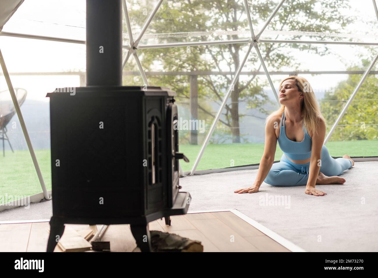 Sportliche Frau, die in einem Geo Dome Glamping Zelt Sport macht Stockfoto