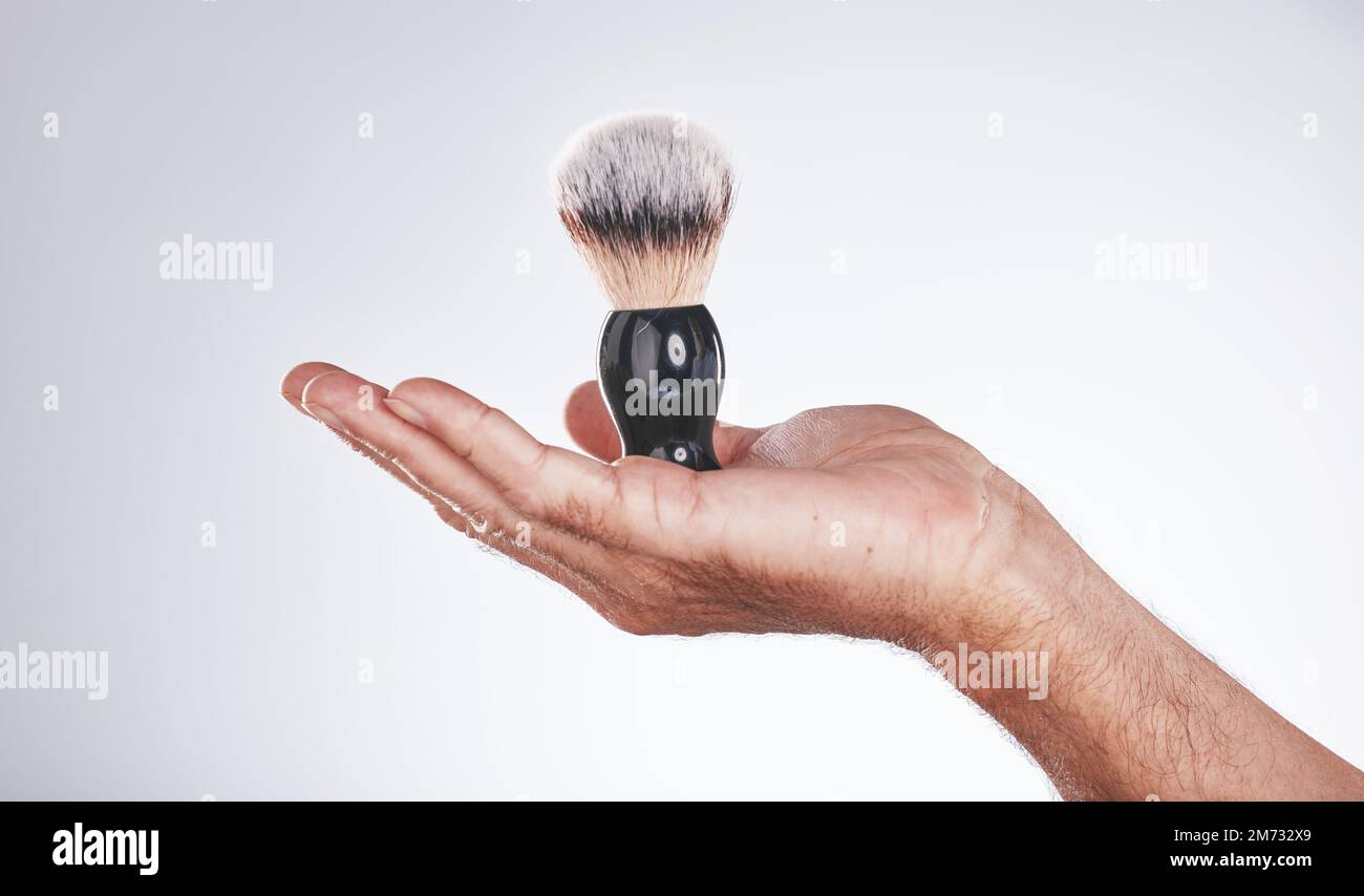 Make-up, Kosmetik und Hand des Bürstenmannes im Studio isoliert auf grauem Hintergrund. Hautpflege, Ästhetik und männliches Modellierungsprodukt Stockfoto