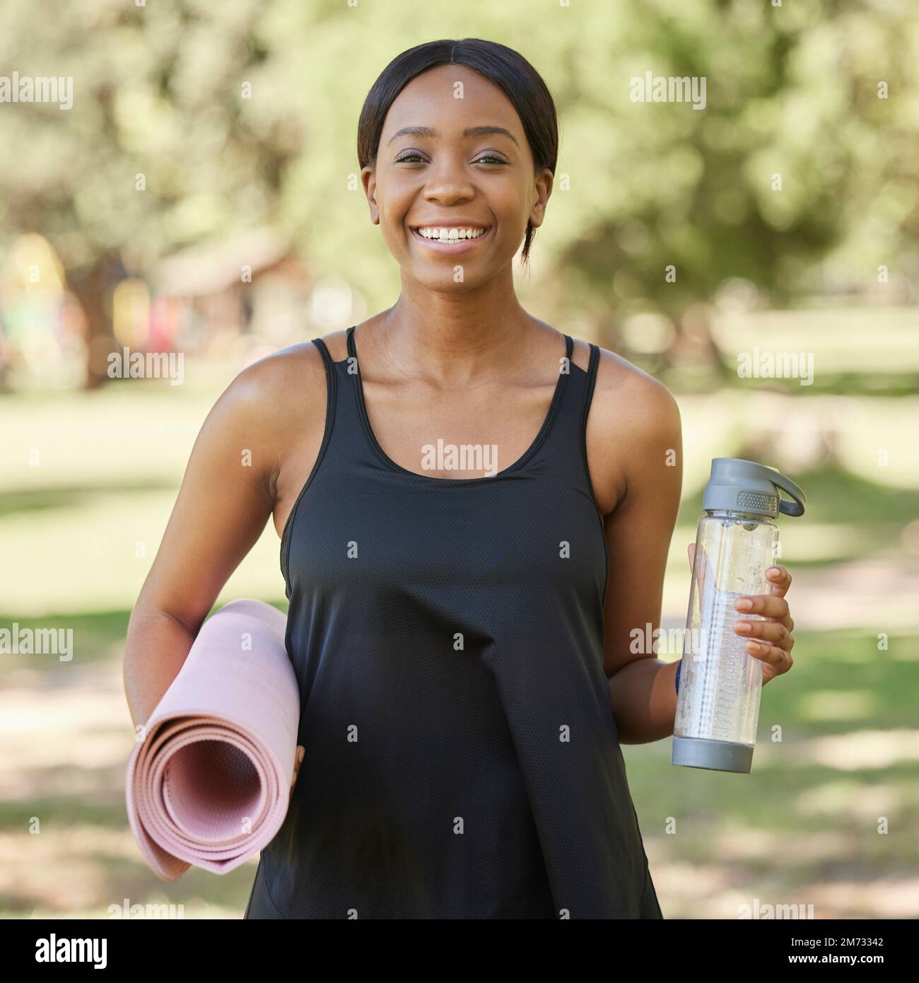 Porträt einer schwarzen Frau im Park mit Yogamatte und Wasserflasche, Lächeln in der Natur für Gesundheit und Fitness. Übung, Zen und Yoga, glückliche Frau Stockfoto