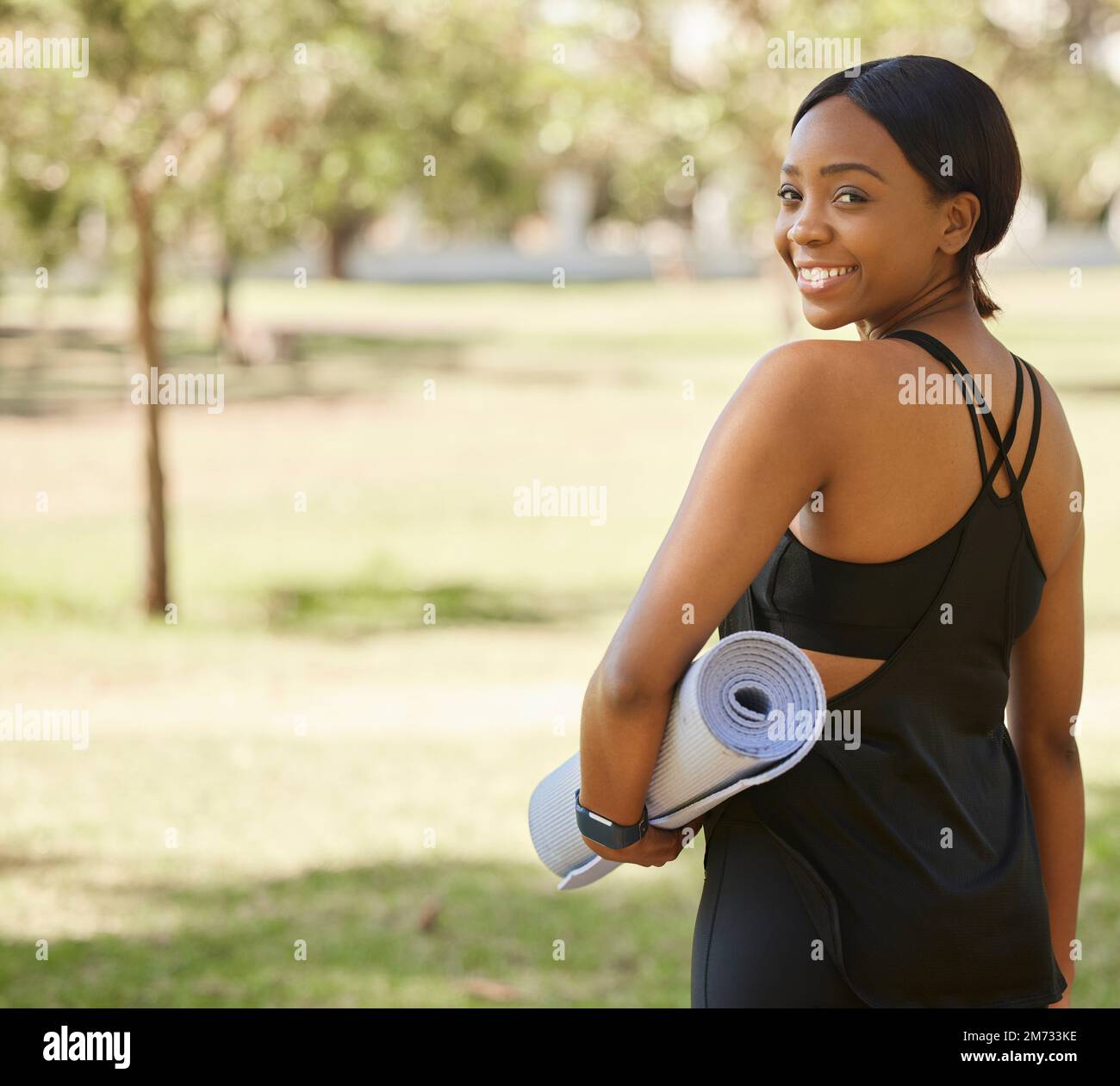 Porträt einer schwarzen Frau im Park mit Yoga-Matte und von hinten lächeln Sie in der Natur für Gesundheit und Fitness. Natur, Zen und Yoga, glückliches Gesicht auf Frau Stockfoto