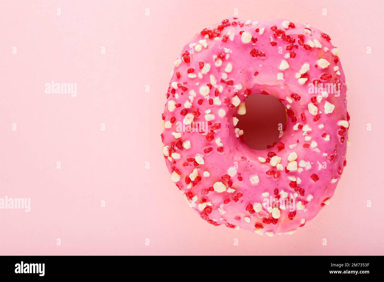 Rosafarbener Donut mit Streuseln auf pinkfarbenem Pastellhintergrund. Ein süßer rosa Donut. Draufsicht. Speicherplatz kopieren Stockfoto