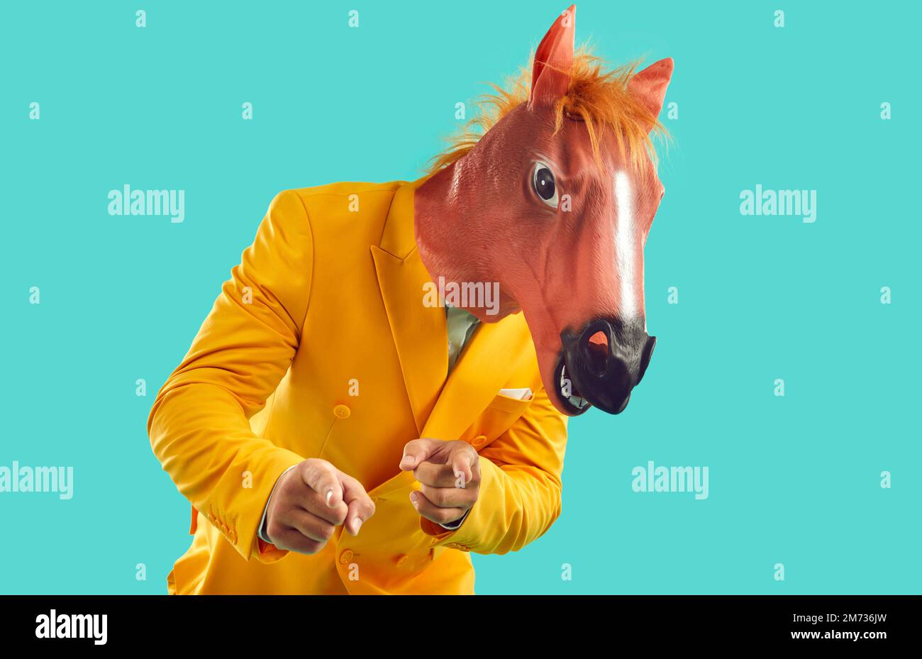 Komischer surrealer Typ in gelbem Partyanzug und Pferdemaske, der mit den Fingern auf die Kamera zeigt Stockfoto