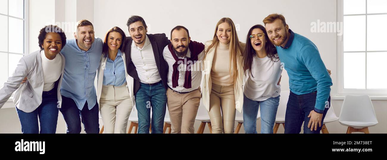 Ein multiethnisches Team glücklicher junger Geschäftsleute, die sich umarmen und lachen Stockfoto