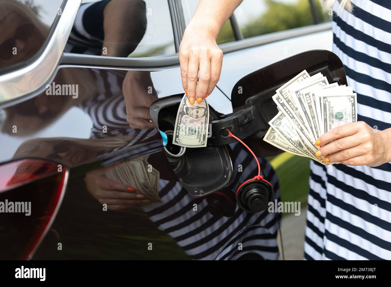 Transportkosten - Einspeisung von Geld in den Kraftstofftank des Autos, Konzept steigender Kraftstoffpreise Stockfoto