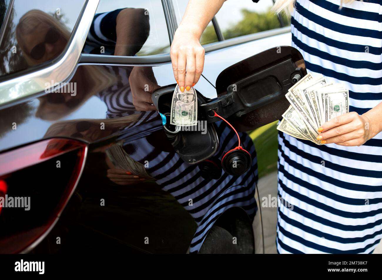 Transportkosten - Einspeisung von Geld in den Kraftstofftank des Autos, Konzept steigender Kraftstoffpreise Stockfoto