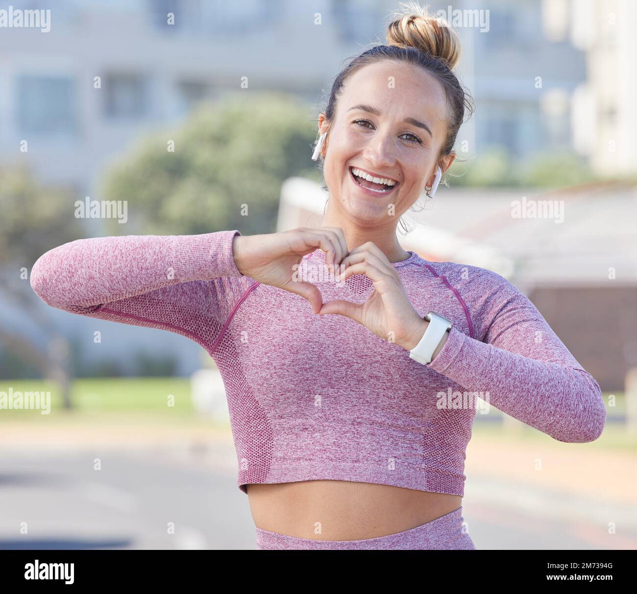 Fitness, Frau und Hand Herzzeichen, glücklich im Porträt und Sport im Freien mit Liebessymbol für sportliche Motivation. Läufer, Freiheit mit Kopfhörern für Stockfoto