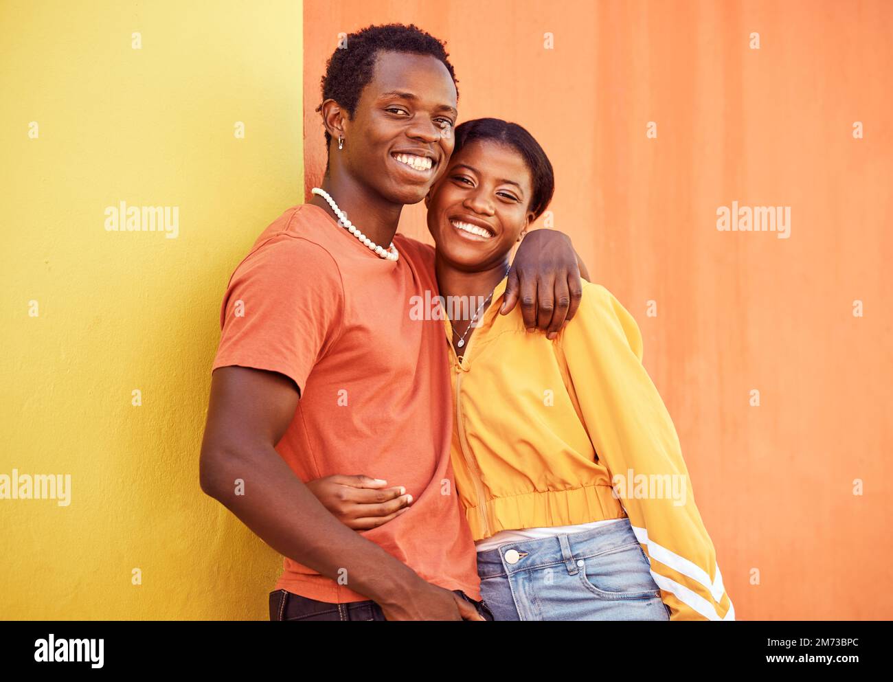 Schwarzes Paar, Jugend und Mode mit Genz, Umarmung und zusammen mit Farbe und Porträt vor dem Hintergrund der Wand. Schwarzer Mann, schwarze Frau und jung mit Stockfoto