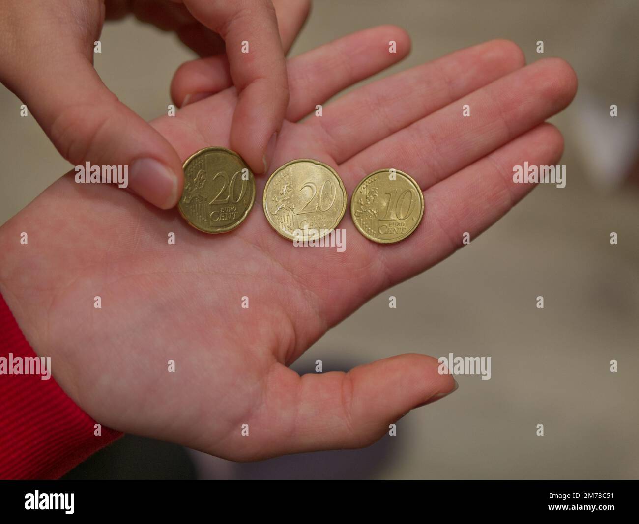 Das Mädchen hält Euro-Münzen im Wert von 10 und 20 Cent in der Hand Stockfoto