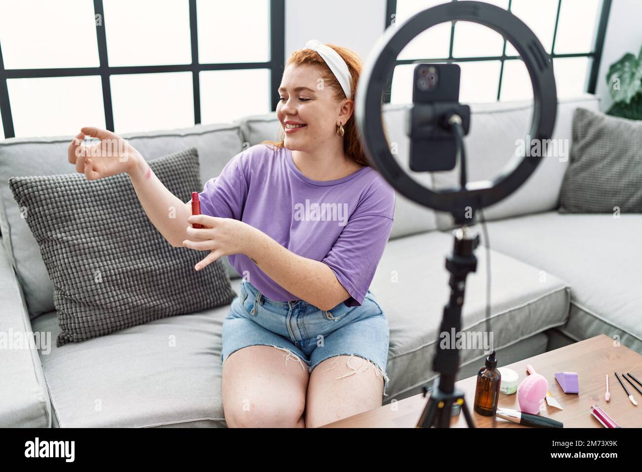 Junge Rotschopf Frau Make-up-Tutorial mit Smartphone zu Hause Stockfoto
