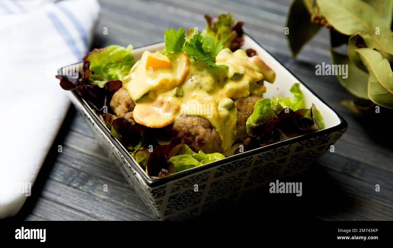 Fleischbällchen mit Currysauce und Salat. Stockfoto