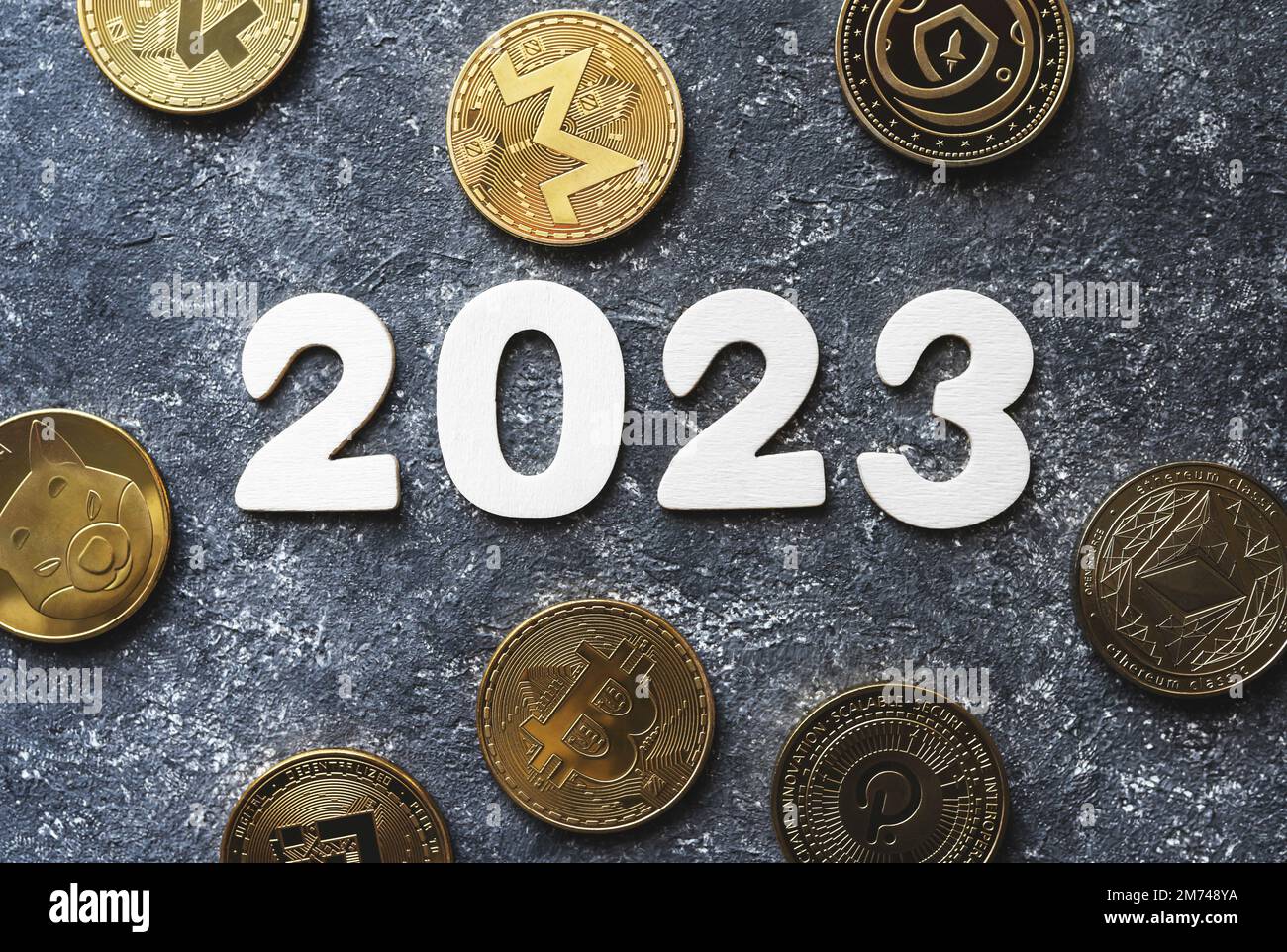 Kryptowährung in 2023. Goldene Kryptomünzen Bitcoin, Ethereum, Shiba, BNB, Monero, Polkadot neben der Jahreszahl auf Betonhintergrund. 2023 Preis, Markttrends, Prognosekonzept. Stockfoto