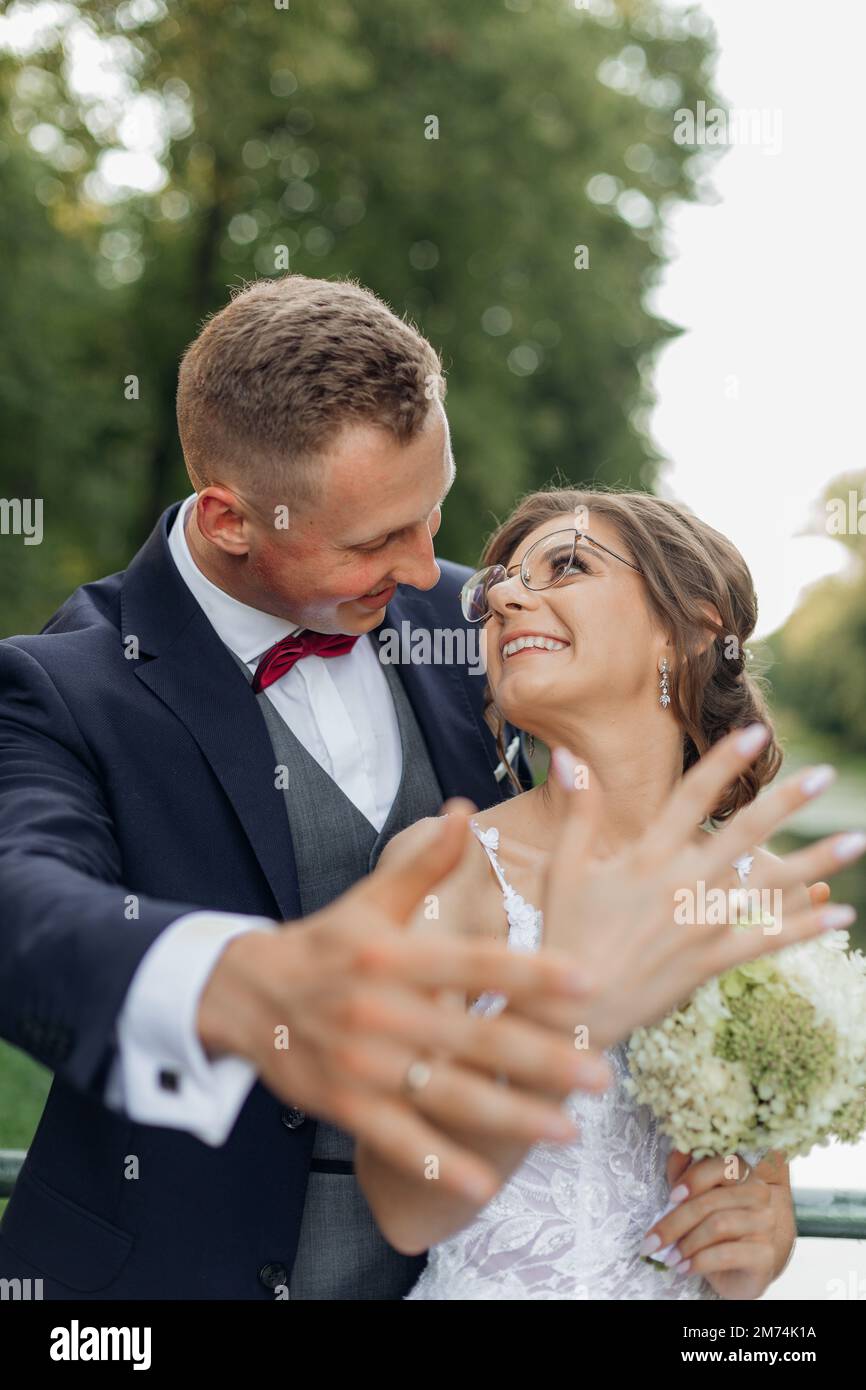 Vertikales glückliches, glückliches, glückliches Ehepaar auf der Hochzeitsfeier mit Eheringen an den Händen im Vordergrund. Stockfoto