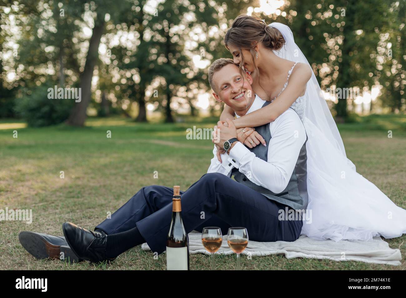 Vertikales frisch verheiratetes Brautpaar im Hochzeitskleid, küsst den Bräutigam, umarmt und trinkt Champagner am Hochzeitstag Stockfoto