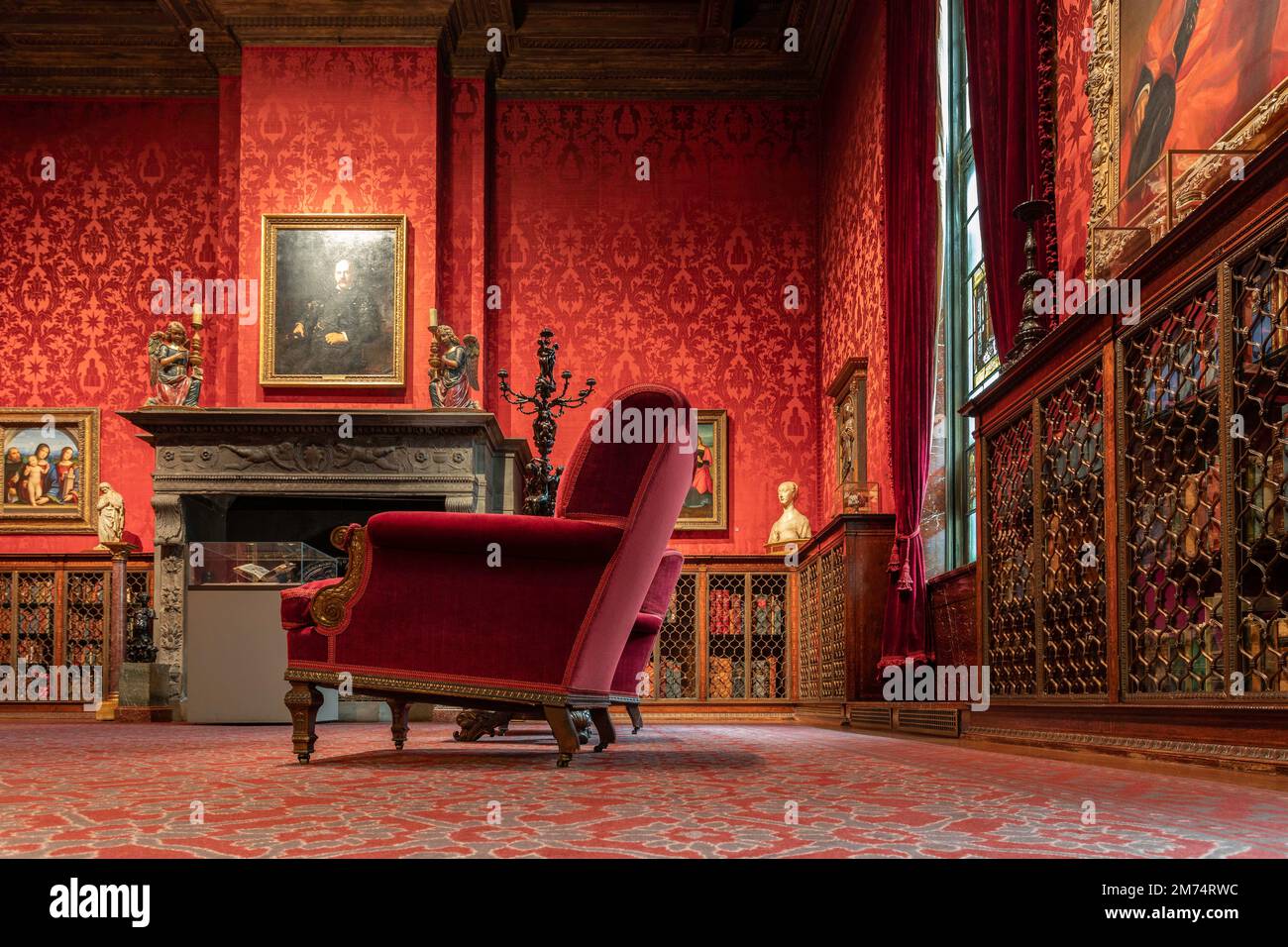 Foto des Innenraums eines der Zimmer der Morgan Library in New York City mit einem roten Samtstuhl und wunderschönen Tapeten an den Wänden. Stockfoto