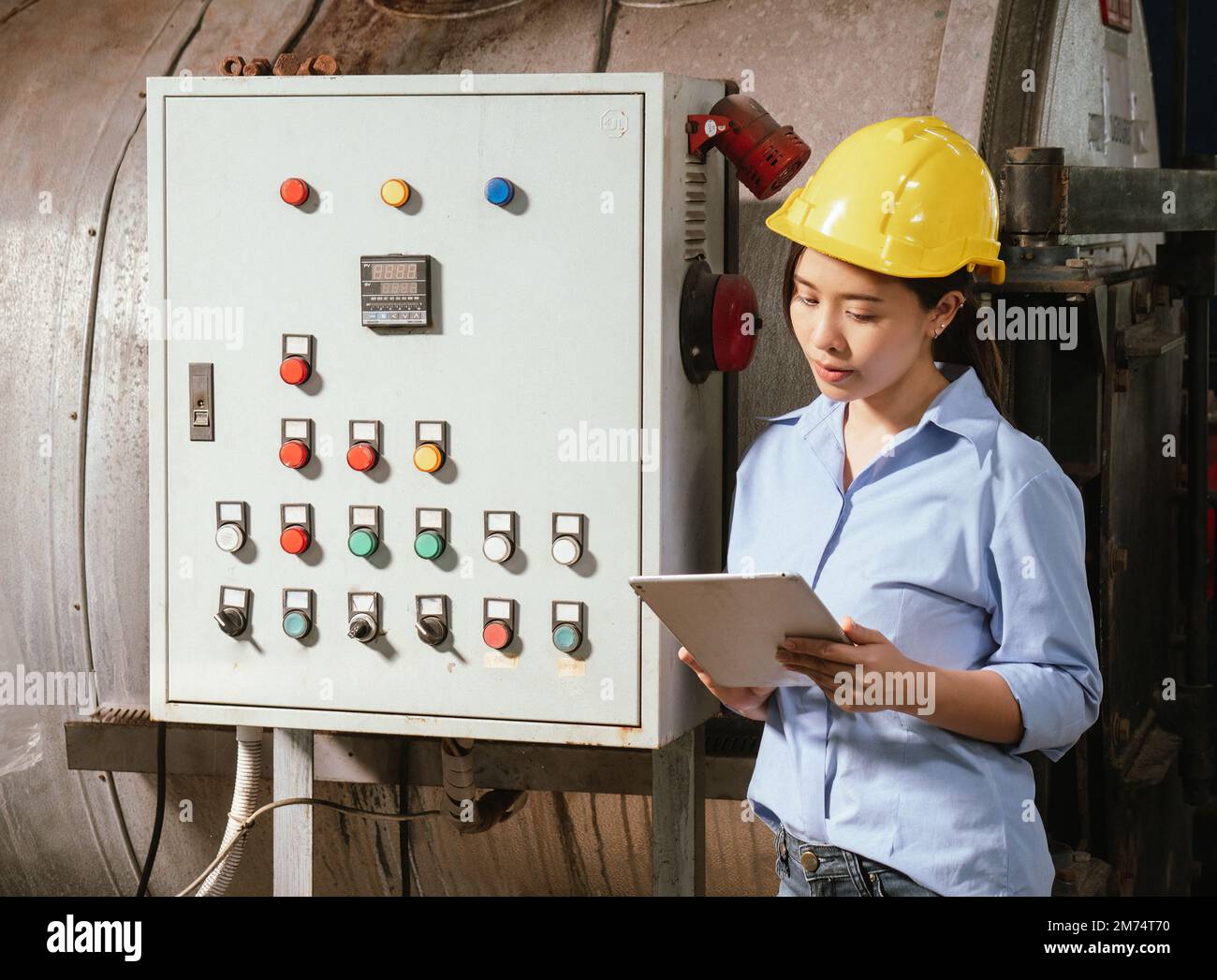 Weibliche Fabrikarbeiterin, die einen Tablet-Computer verwendet, um den Maschinenbetrieb in einer Getränkefabrik zu überprüfen. Stockfoto