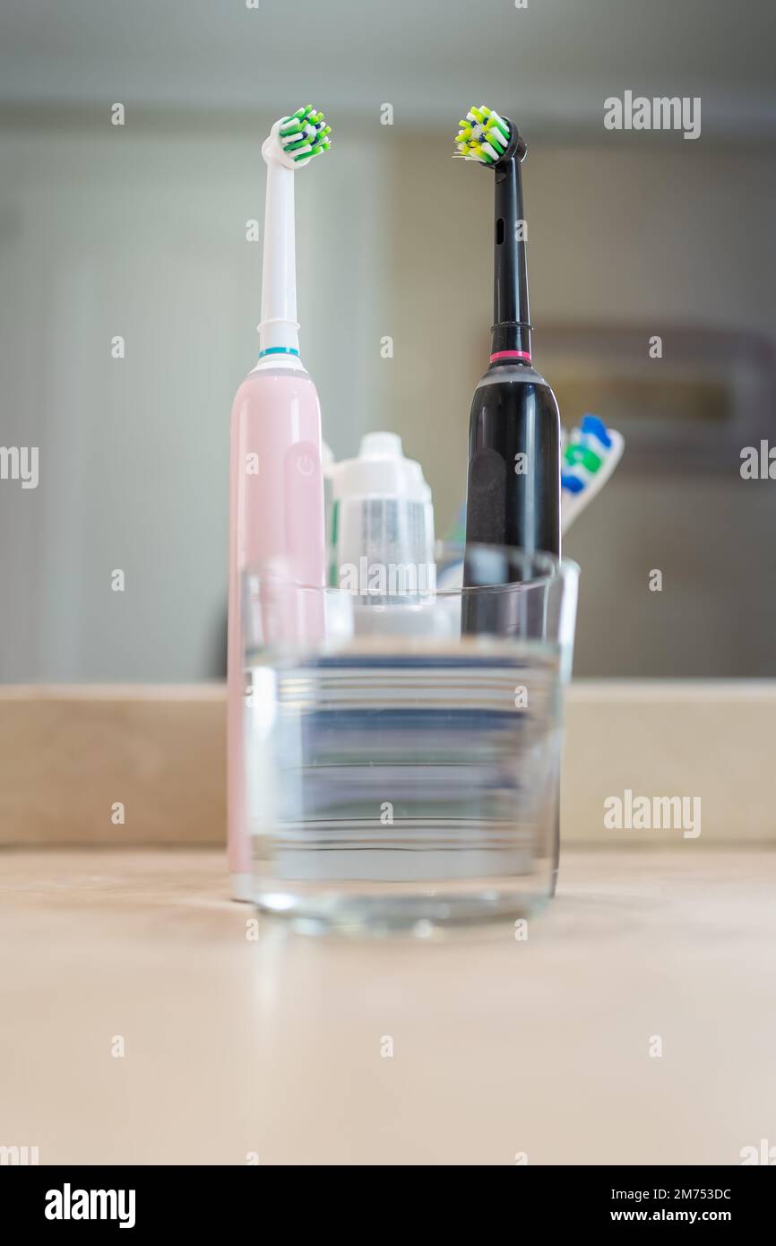 Elektrische Zahnbürsten mit einem Glas Wasser und anderen Gegenständen für die Zahnhygiene, Foto mit Kopierraum. Stockfoto