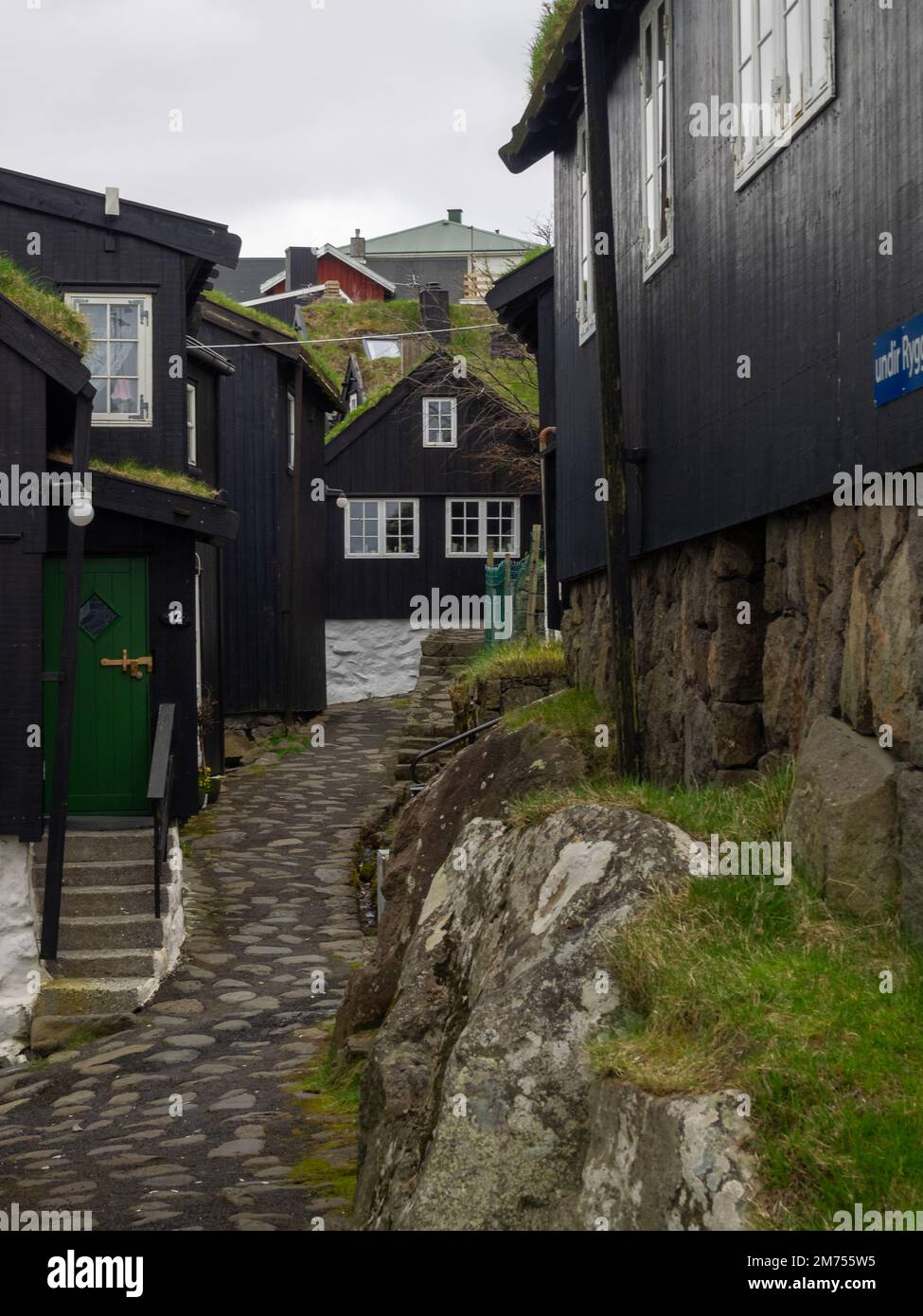 Alte Kopfsteinpflasterstraße in Tórshavn und Häuser mit schwarzen Holzdächern Stockfoto