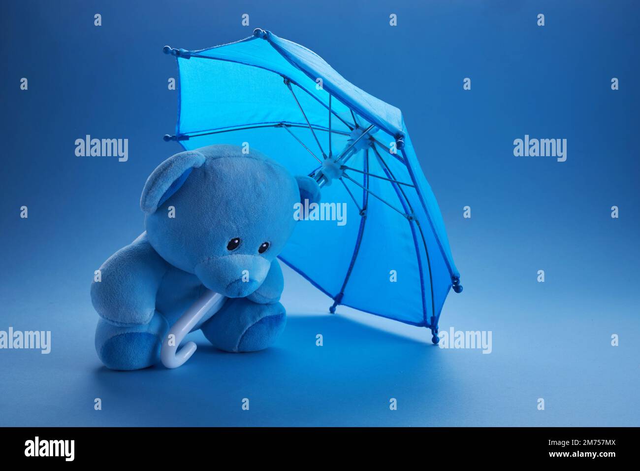 Blauer Teddybär mit Regenschirm auf blauem Hintergrund. Blue monday Konzept. Stockfoto