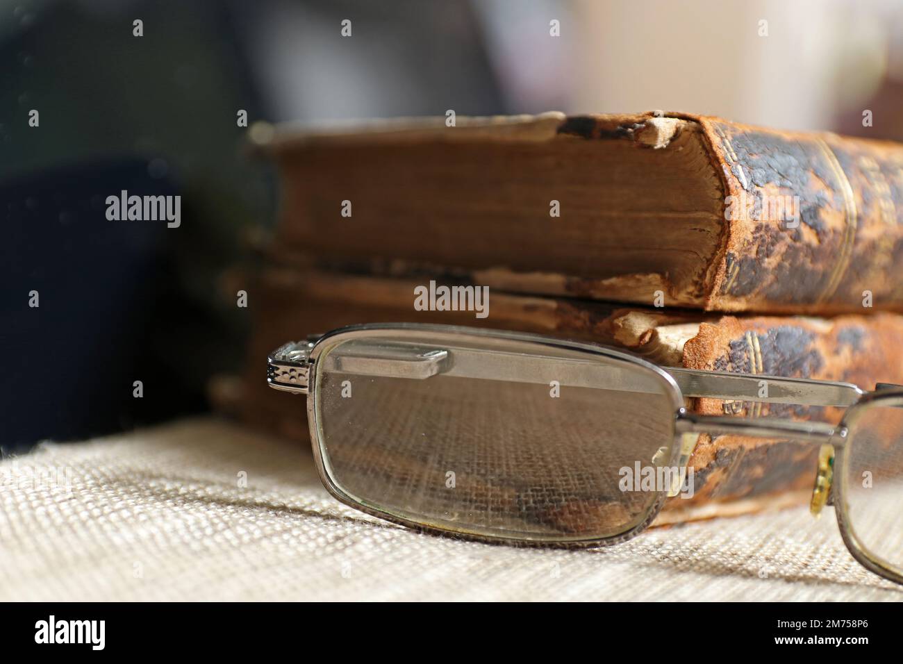 Alte Bücher mit Vintage-Brille vor verschwommenem Hintergrund. Stockfoto