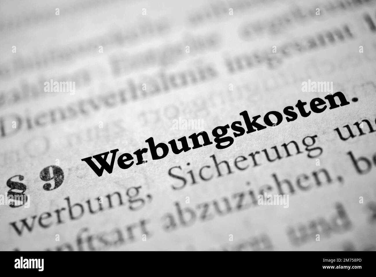 Eine Kurzfassung des deutschen Wortes Werbungskosten in fetter Schrift, umgeben von verschwommenen Wörtern Übersetzung - einkommensbezogene Aufwendungen Stockfoto