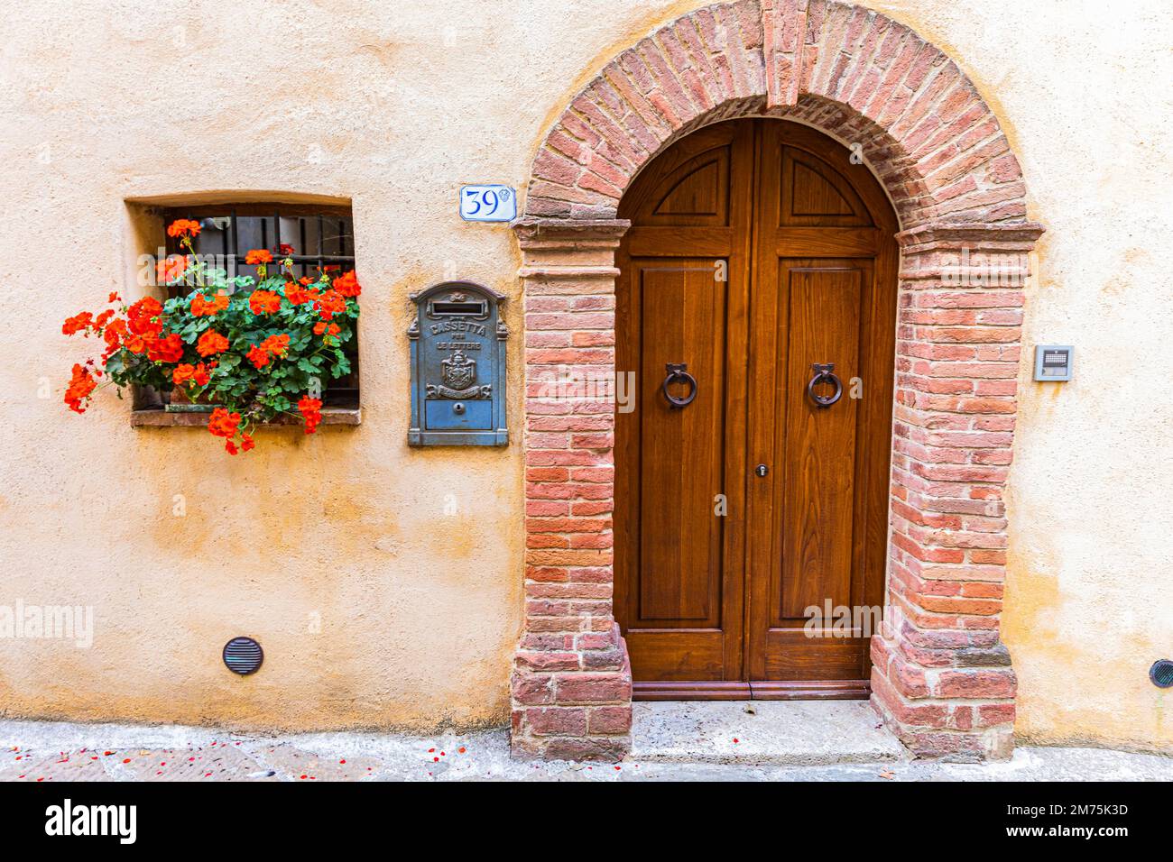 Vordertür mit rundem Bogen, Blumenfenster und dekorativem Briefkasten, Trequanda, Toskana, Italien Stockfoto