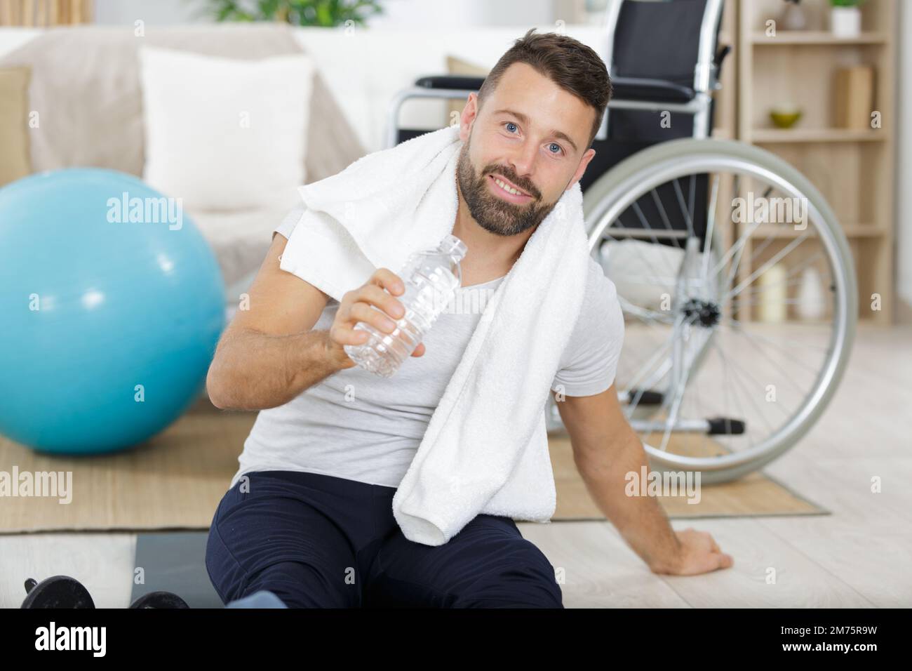 Mann mit einer Flasche Wasser-Kurzhantel und einem grünen Handtuch Stockfoto