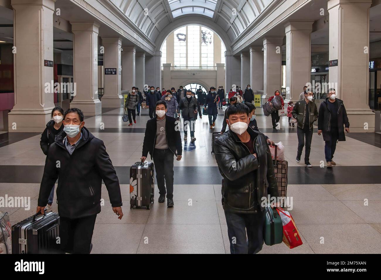 Passagiere mit Gesichtsmasken tragen ihr Gepäck am ersten Tag des chinesischen Frühlingsfestivals in Wuhan am Bahnhof Hankow. Am Samstag, dem ersten Tag des diesjährigen Frühjahrsfestes, werden voraussichtlich rund 6,3 Millionen Fahrten durch China unternommen, so der nationale Eisenbahnbetreiber China State Railway Group. China hat kürzlich sein epidemisches Kontrollmanagement optimiert, und auch epidemische Maßnahmen für Reisen wurden letzten Monat optimiert. Reisende benötigen keine negativen Nukleinsäuretests oder Gesundheitscodes mehr, sind nicht verpflichtet, sich einem Nukleinsäuretest zu unterziehen Stockfoto